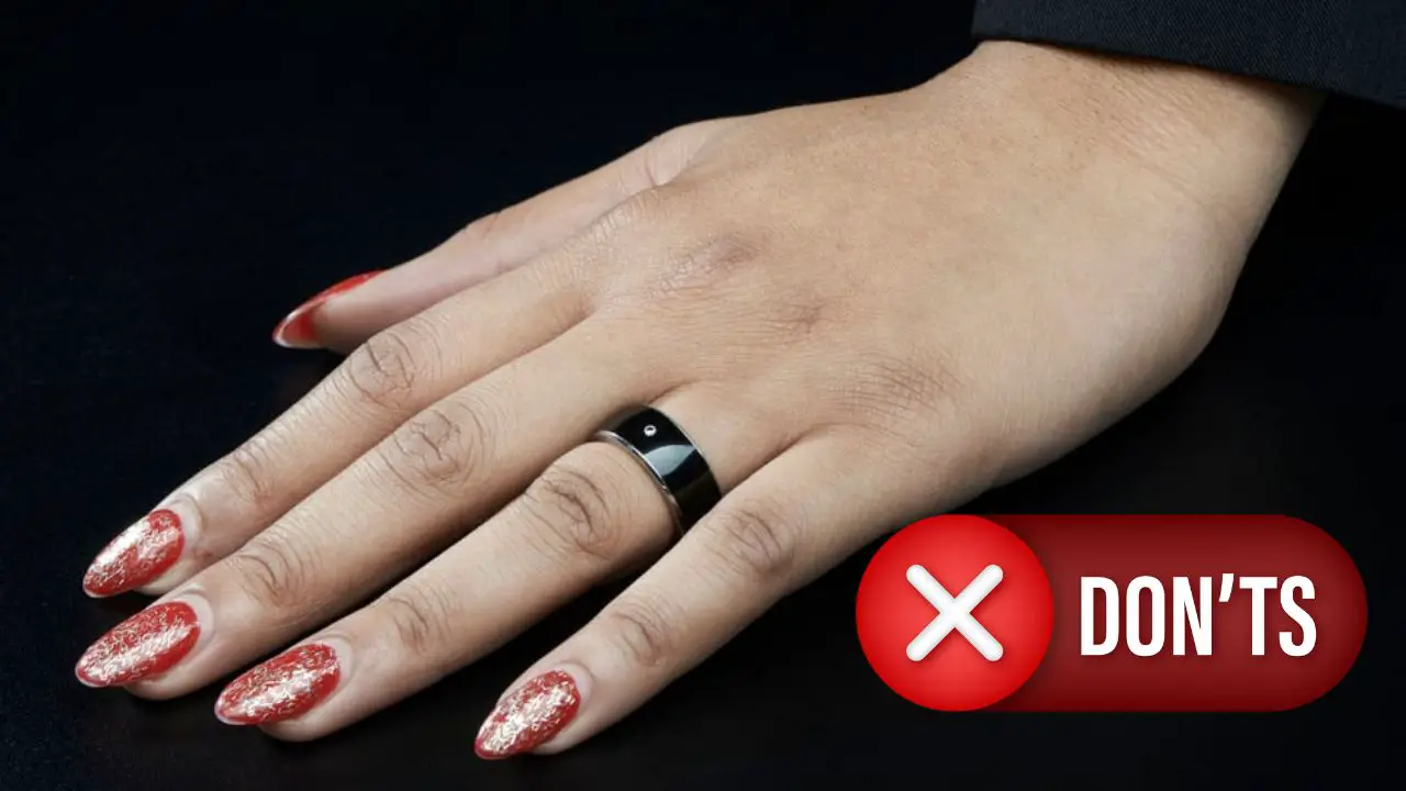 A hand sporting a sleek black smart ring on the index finger against a dark background